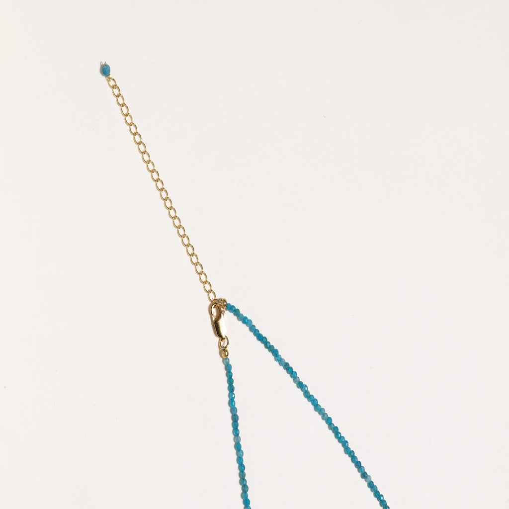 Dainty teal apatite beaded necklace with a single freshwater pearl centerpiece flanked by two small gold beads, adjustable gold clasp.