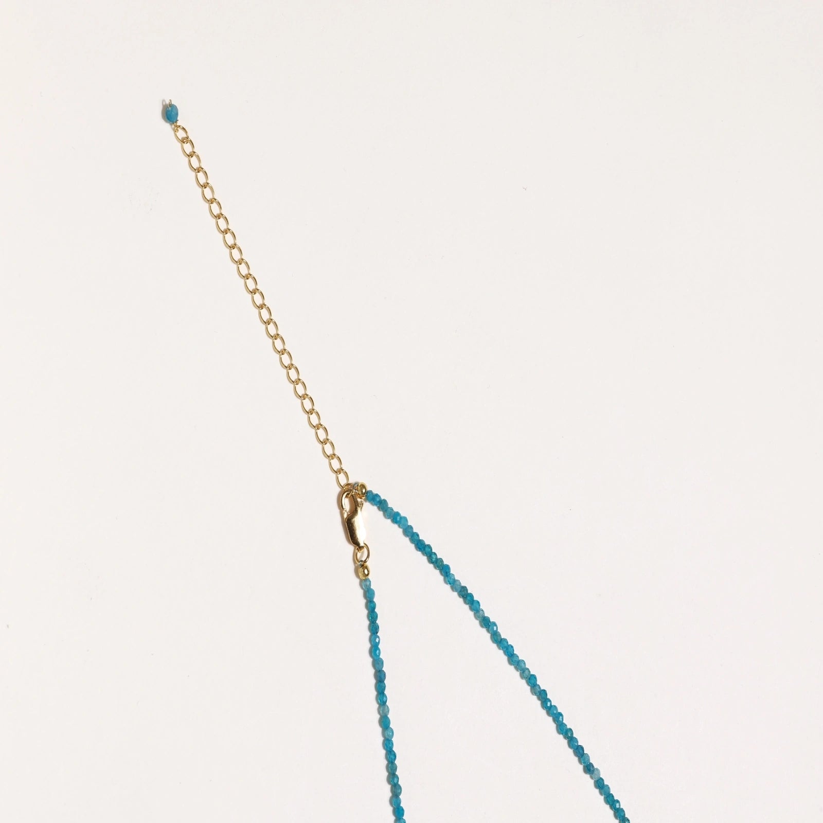 Dainty teal apatite beaded necklace with a single freshwater pearl centerpiece flanked by two small gold beads, adjustable gold clasp.